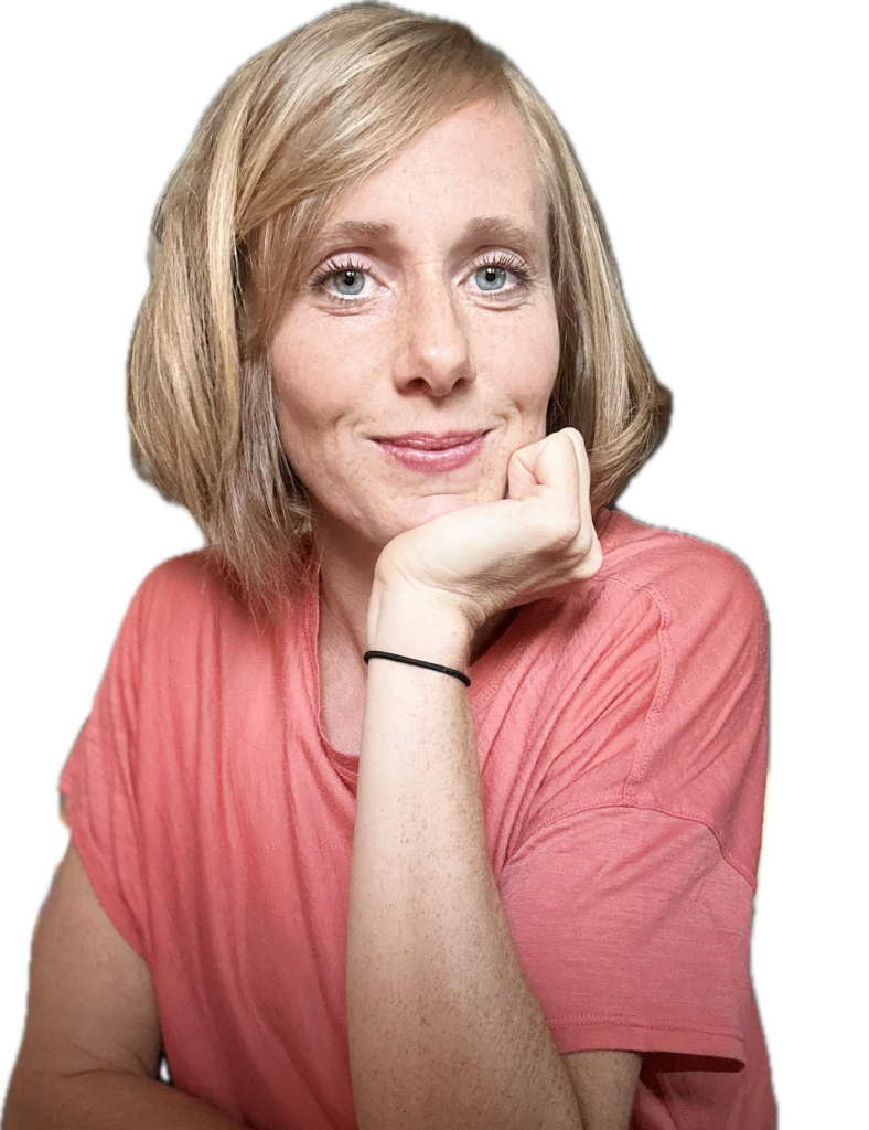 Annika Sukup lächelt, stützt ihr Kinn auf die Hand, trägt ein korallfarbenes Oberteil.